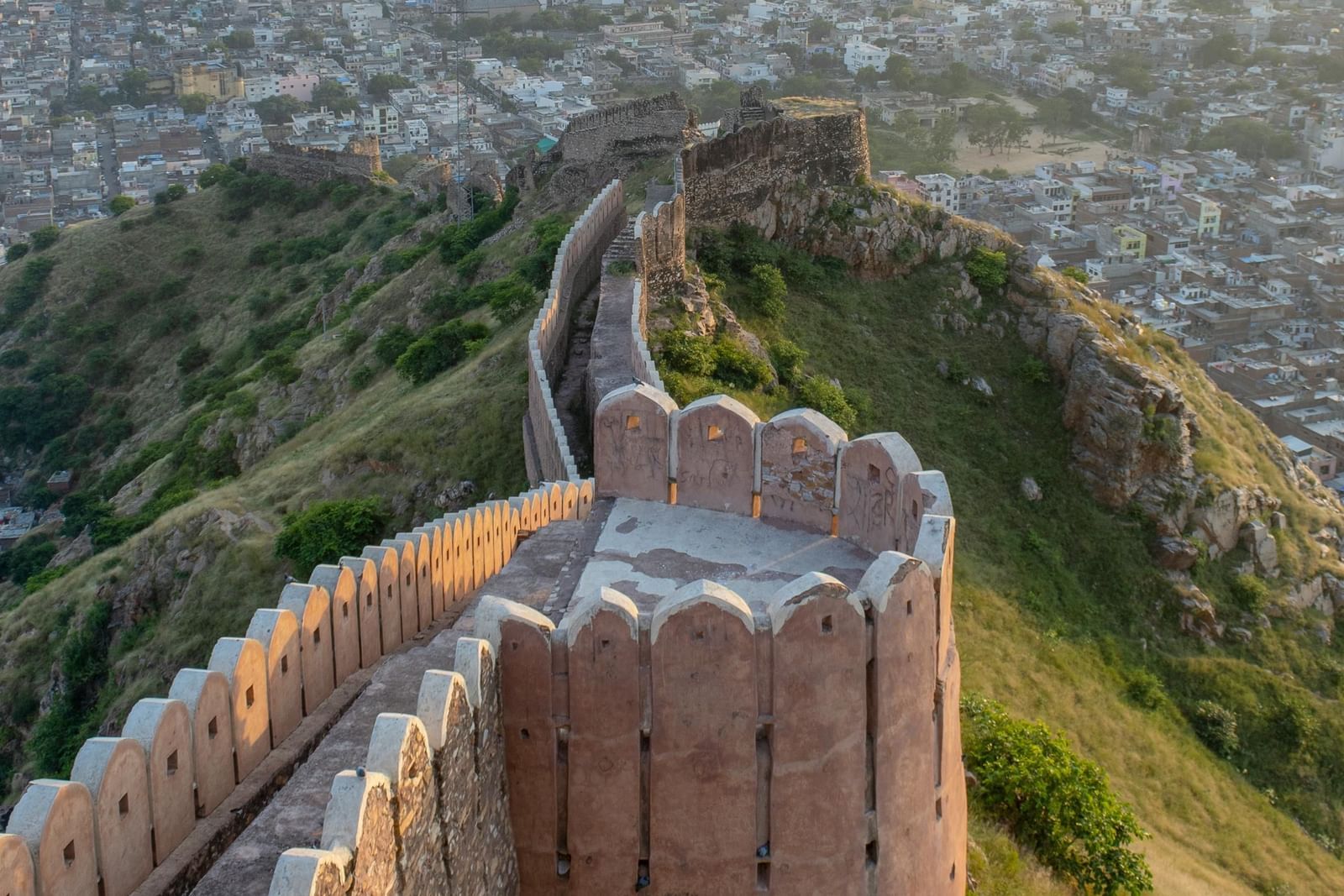 Ancient fort wall snakes across a hilltop, overlooking a sprawling city