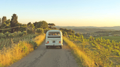a car Travelling on the muddy road with grass on either side and blue sky in the background