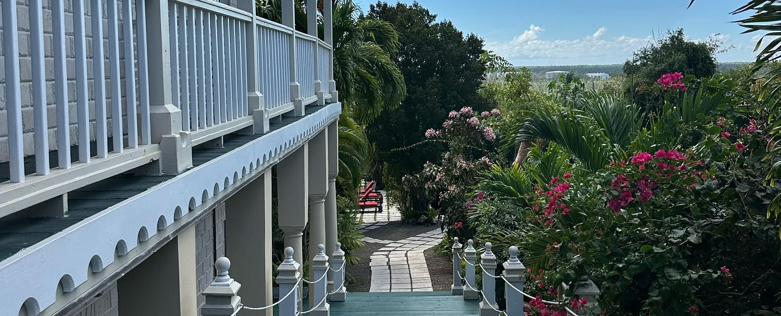 Exterior corridor with white railings and garden path below | A Stone's Throw Away