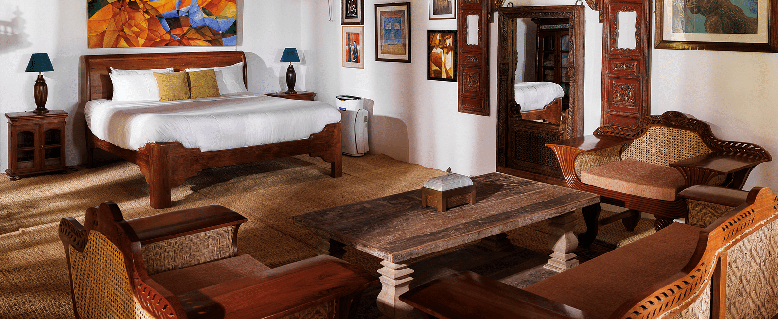 A wooden interior room with wooden furnitures such as a bed, a sofa set, a coffee table, and paintings - BluSalzz Villas - Muhamma Resort, Alleppey