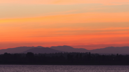 A twilight view of a boat travelling towards the camera with different hues in the sky after the sunset.