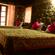 A cosy bedroom with rustic stone walls, beds made with patterned linens, bright pink pillows, and warm ambient lighting.