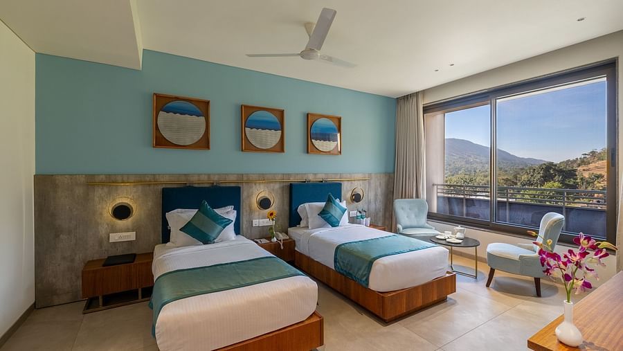 view of two twin beds and chairs near the window of a Deluxe Room at Stone Wood Hotel, Kumbhalgarh