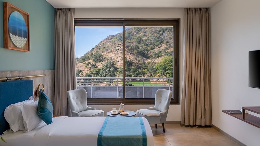 view of a king size bed and balcony of a Deluxe Room at Stone Wood Hotel, Kumbhalgarh