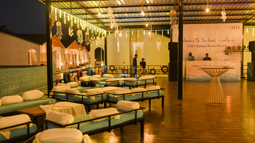 A view of the seating arrangement at Urban Dhaba, the best restaurant in Daman, featuring a reception desk, dream catchers, LED lights and people in view at VITS Daman Devka Beach.