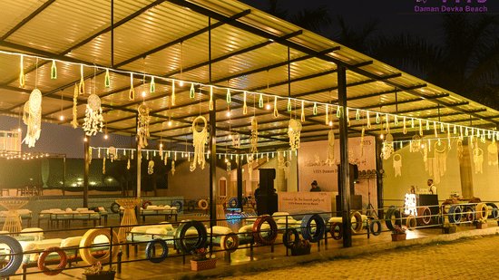 An outside view of Urban Dhaba that can be used as one of the best banquet halls in Daman with LED lights, dream catchers, and seating arrangement in view at VITS Daman Devka Beach.