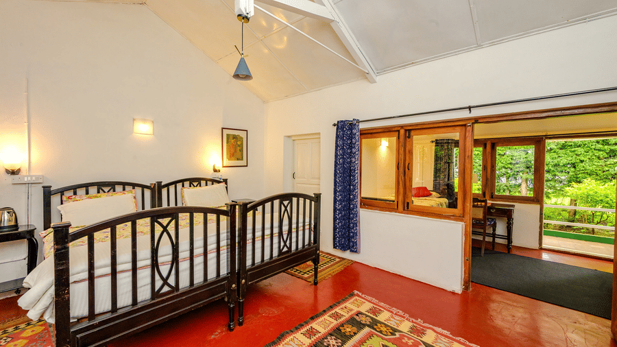 Cherry Blossom room at Wallwood Garden - 19th Century, Coonoor with twin beds, high ceiling, patterned rugs and garden-facing windows.