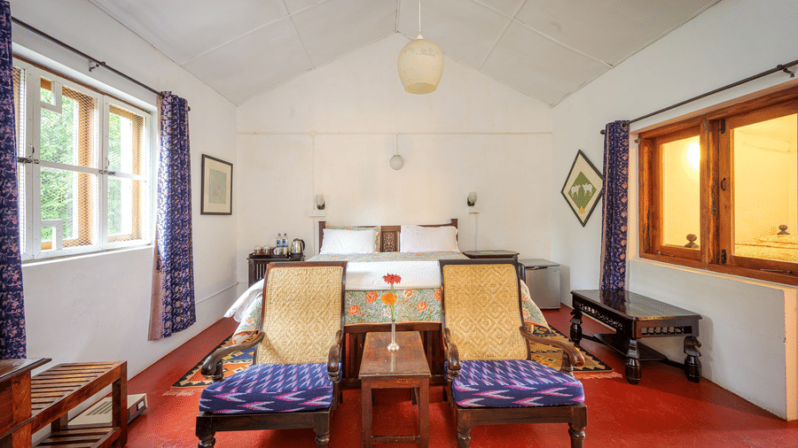 Symmetrical view of the Silver Oak room at Wallwood Garden - 19th Century, Coonoor with double bed, seating area and large windows.