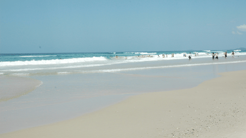 A serene beach with calm waters and very few people seen during a sunny day | Tourist Places in Allapuzha