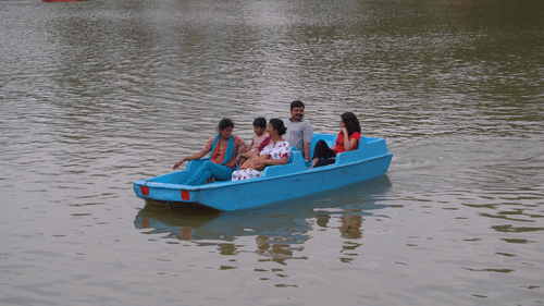 A group of people enjoying a relaxing pedal boat ride on a calm lake, surrounded by nature - Black Thunder, Coimbatore