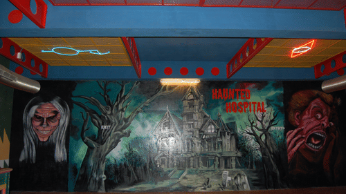 A mural of a haunted hospital featuring eerie faces, a haunted house, and creepy trees with the words HAUNTED HOSPITAL on the wall at Black Thunder, Coimbatore