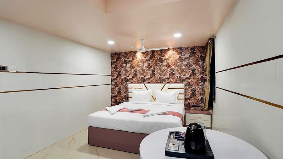 A king size bed placed behind a round table in Suite at Hotel Regal Heaven, Pune.