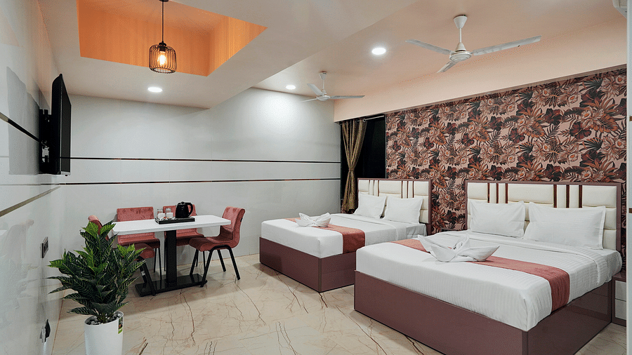 Two seperate king size beds placed in front of television in the Family Room at Hotel Regal Heaven, Pune.