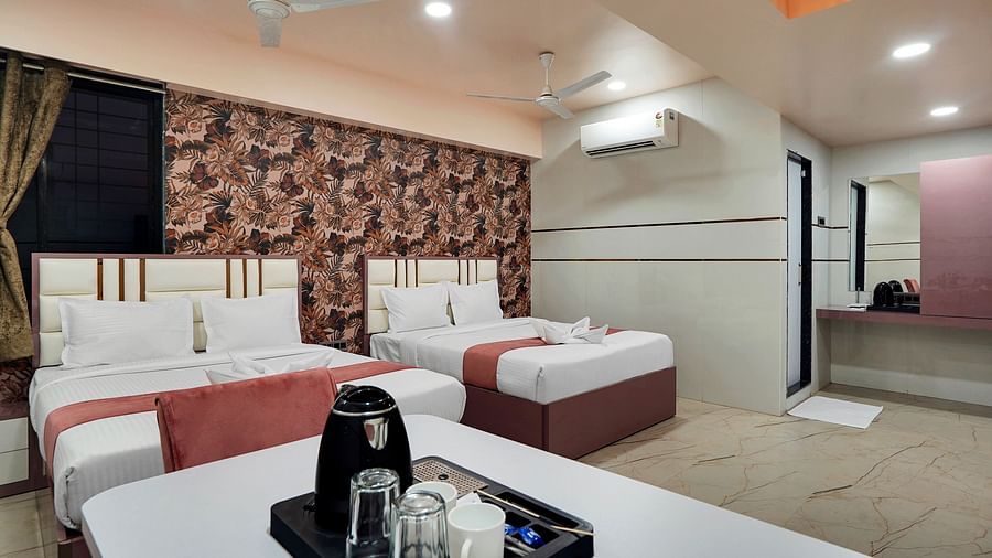 Two king size beds placed in front of table with tea & coffee maker in Family Room at Hotel Regal Heaven, Pune.