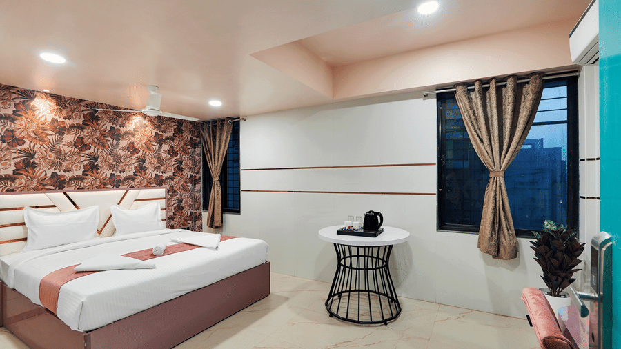 A king size bed near a round table in Suite at Hotel Regal Heaven, Pune.