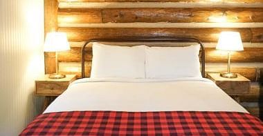 A room with a double bed and side tables with night lamps placed on it -Shaver Lake Village Hotel.