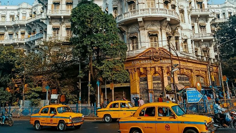An image of the streets of Kolkata with yellow taxis and a building in the background