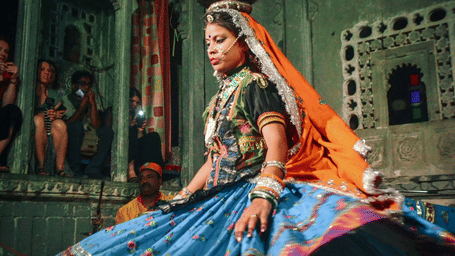 A woman dancer performing at Bagore Ki Haveli Cultural Show during Lok Dharohar while balancing a pot on her head.