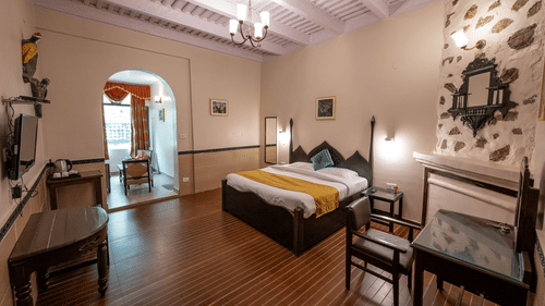 Side view of the spacious standard room with a cosy bed and a TV mounted on the wall at The Pavilion, Nainital