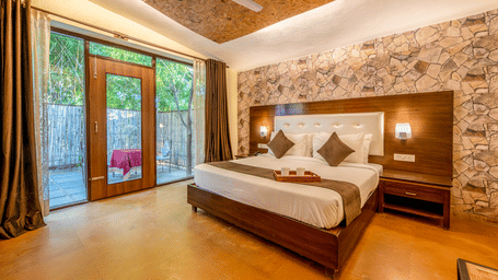 Room with wooden headboard and glass doors at Valley by Grassfield, a resort in Jaipur.
