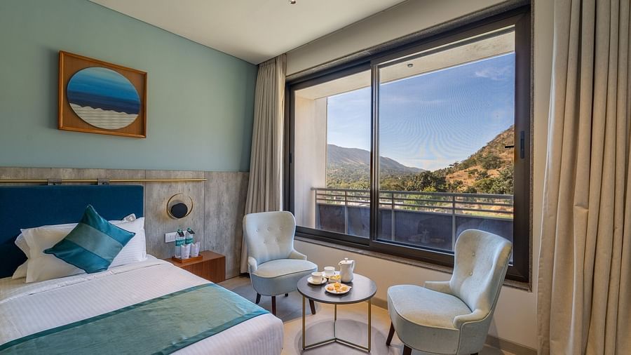 view of a king size bed and seating area near the window of a Deluxe Room at Stone Wood Hotel, Kumbhalgarh