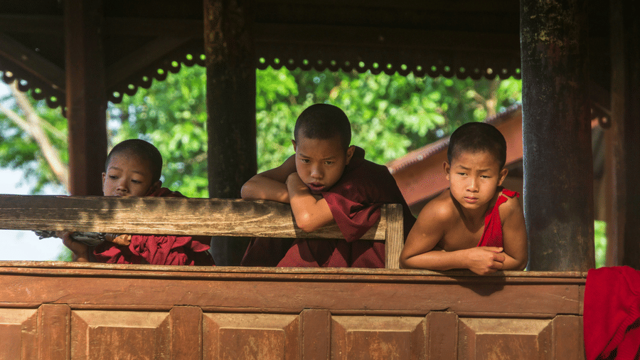 Three buddhist kids looking outside from a monastery 