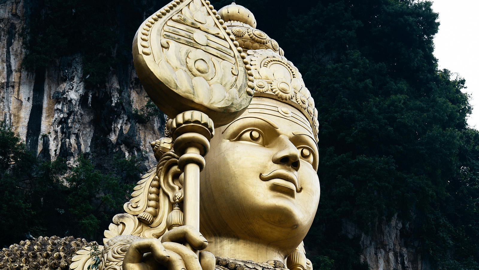 A golden statue of a Hindu God holding a sword.