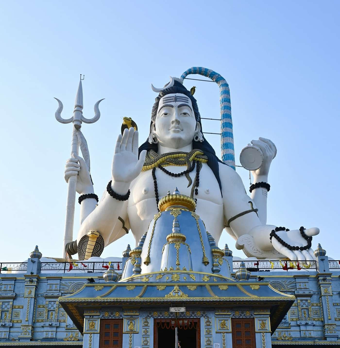 a statue of lord shiva hoding a trident and a damru