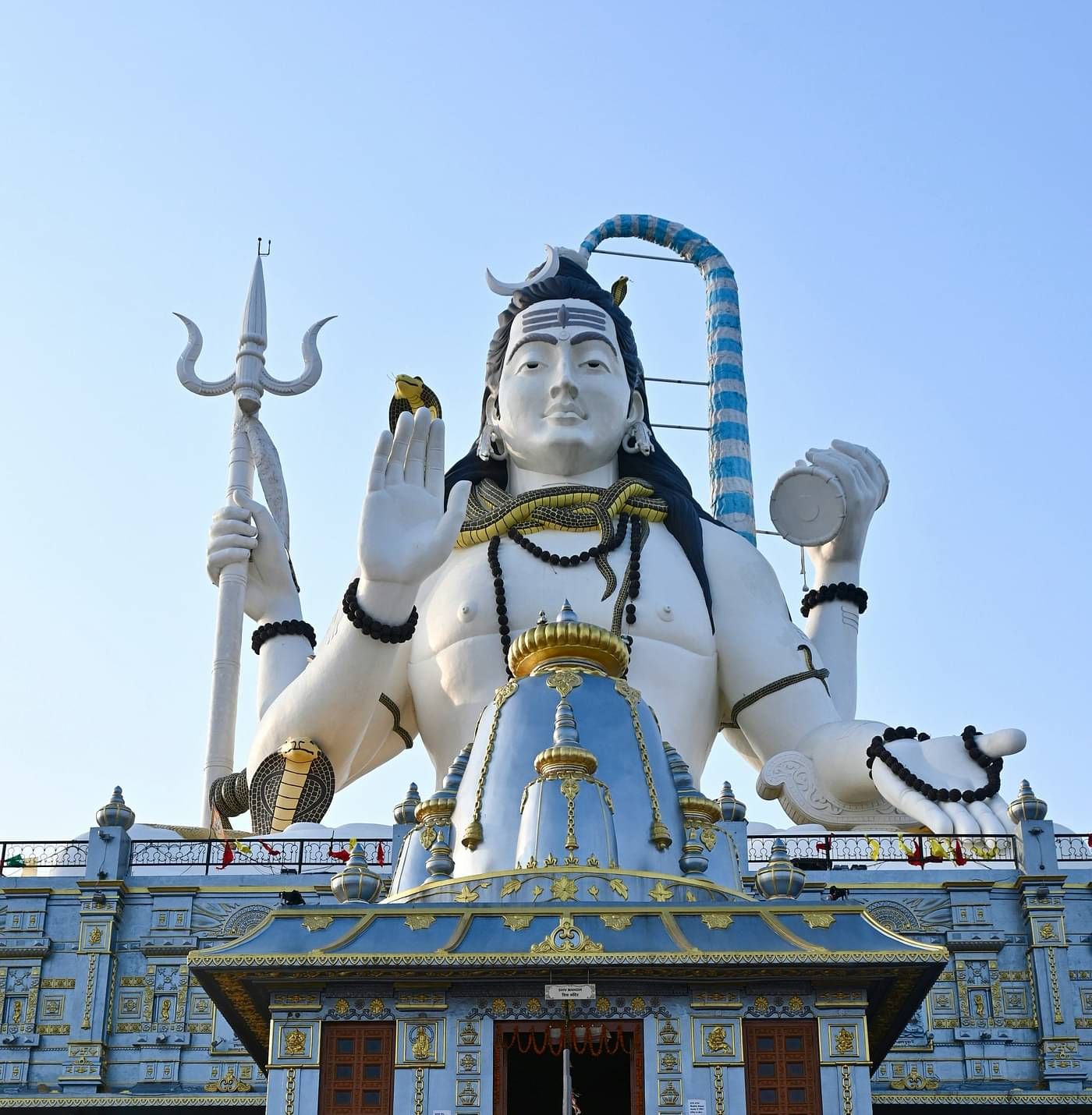 a statue of lord shiva hoding a trident and a damru