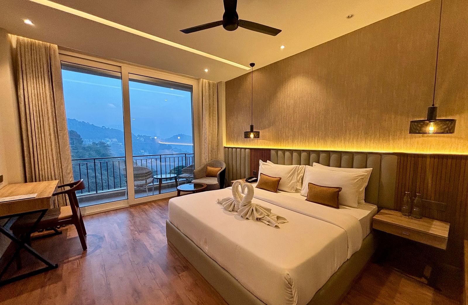 Elegant bedroom with large windows, wooden accents, and a scenic balcony view – ARNISA Boutique Hotel