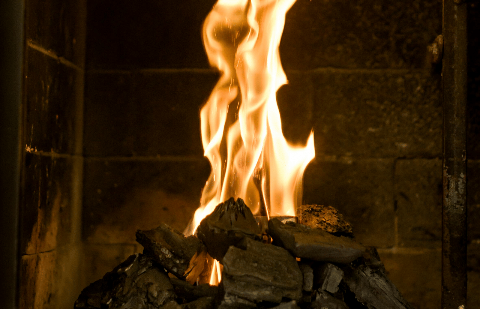 A fireplace with burning charcoal and flames erupting from it.