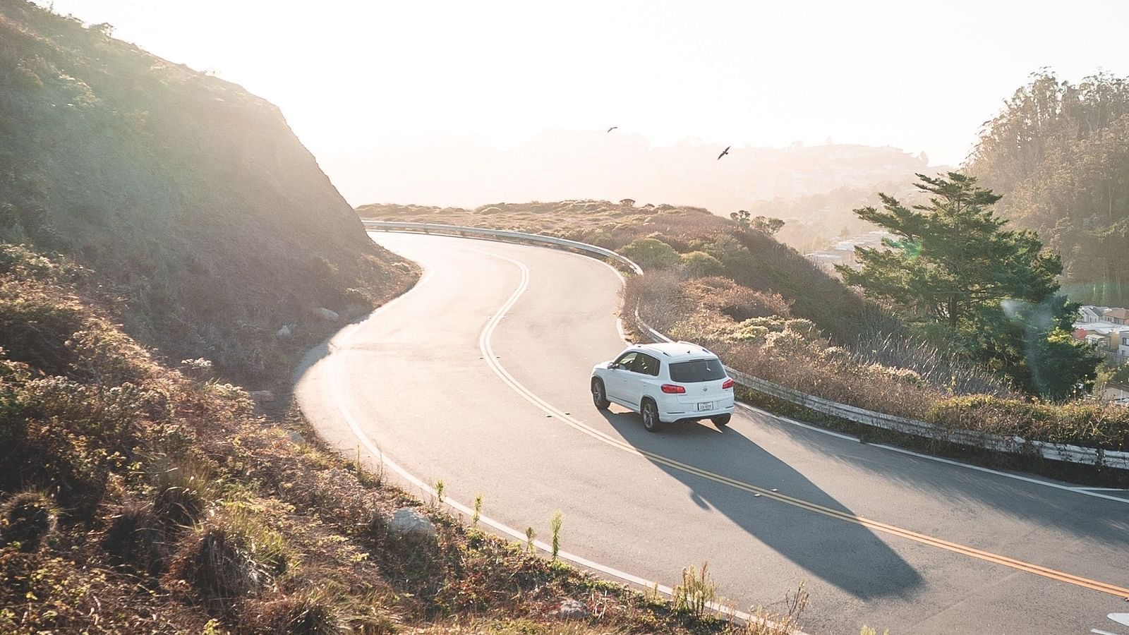a car on the way to a hill with blue sky in the background
