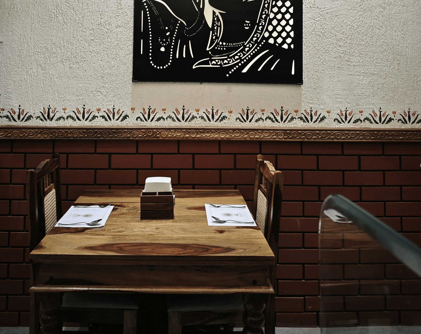Close-up of a framed artwork hanging above a wooden dining area.