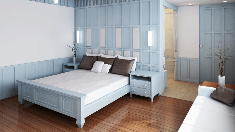 Hill Villa bedroom at Symphony Oceanus Bay Beach Resort & Spa with a pale blue panelled bed and wall, white linens, 4 pillows, and an ensuite bathroom beyond.