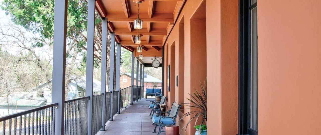 Patio of The Groveland Hotel, surrounded by trees, with benches and potted plants placed in the patio.