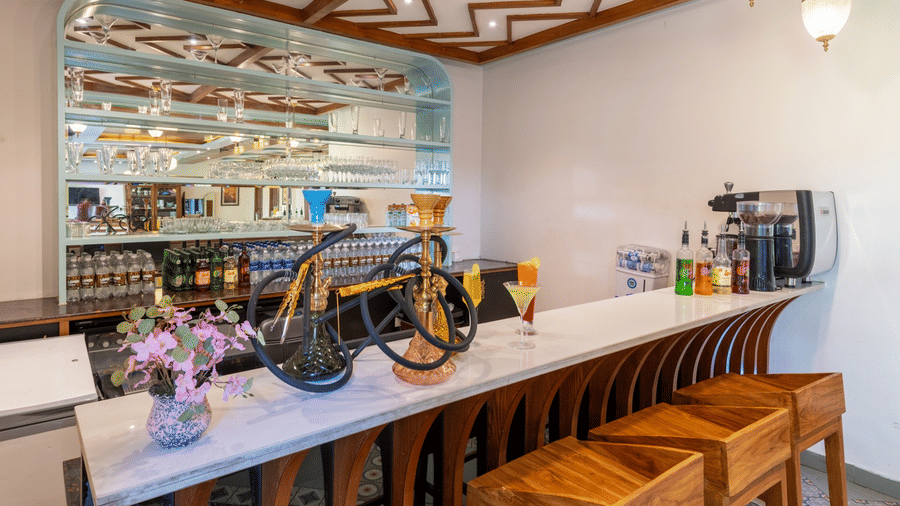 A modern bar area at Quality Inn with a marble counter, wooden stools, and decorative hookahs on display.