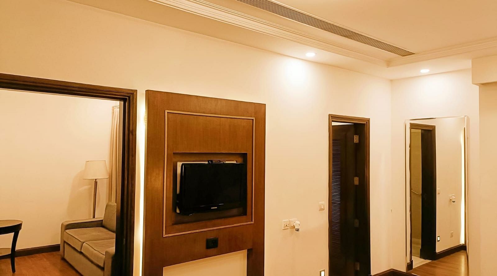 Suite showcasing amenities such as wall-mounted television, bathroom, full-size wall-mounted mirror, and separate living room at Inde Signature Tower, Gurgaon