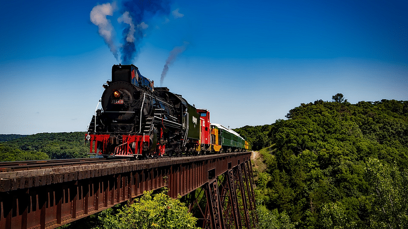 A locomotive train running amidst lush green landscapes