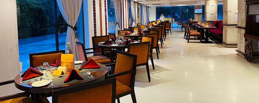 A restaurant interior with multiple tables and chairs arranged for guests.