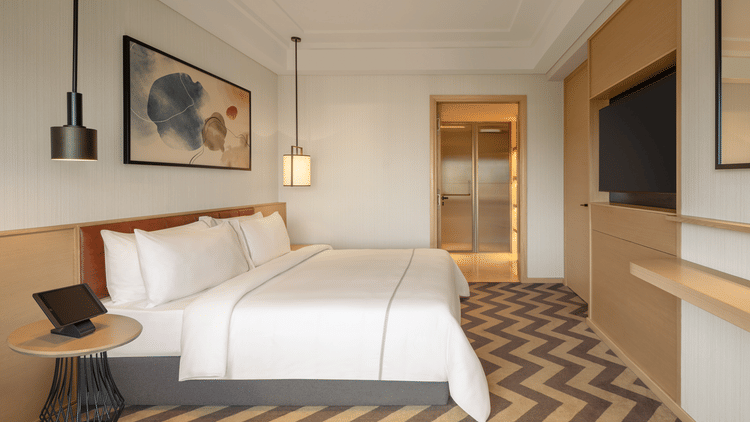 Side view of a luxurious suite room featuring a cozy bed and elegant bedside lamps at The Residency Chennai