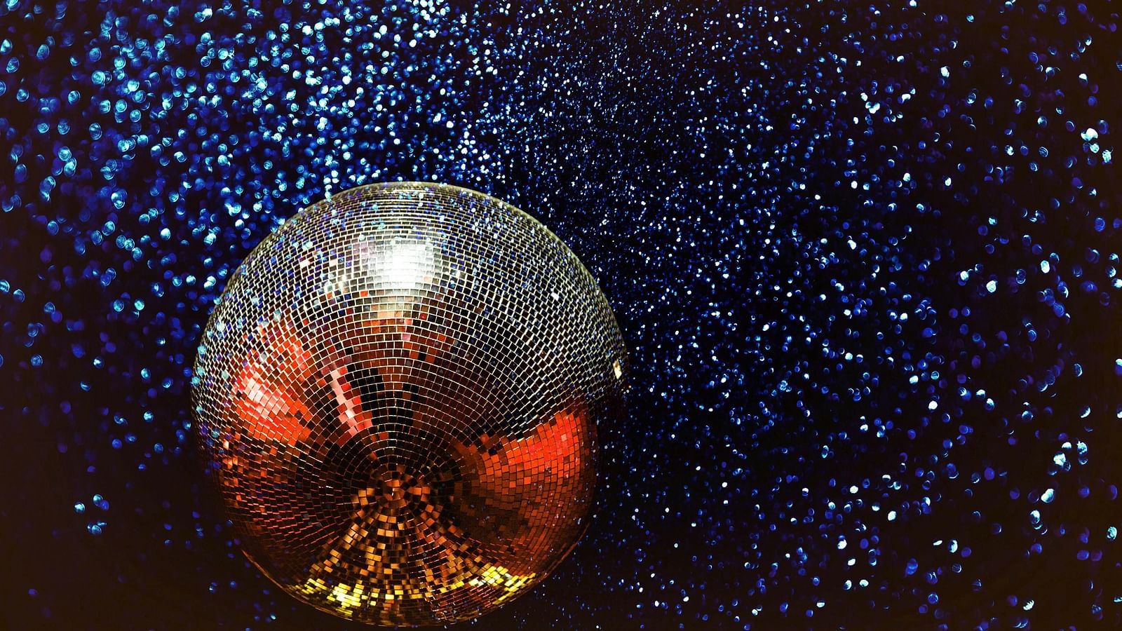 Sparkling sphere on a dark, textured surface, reflecting light with a fiery glow.