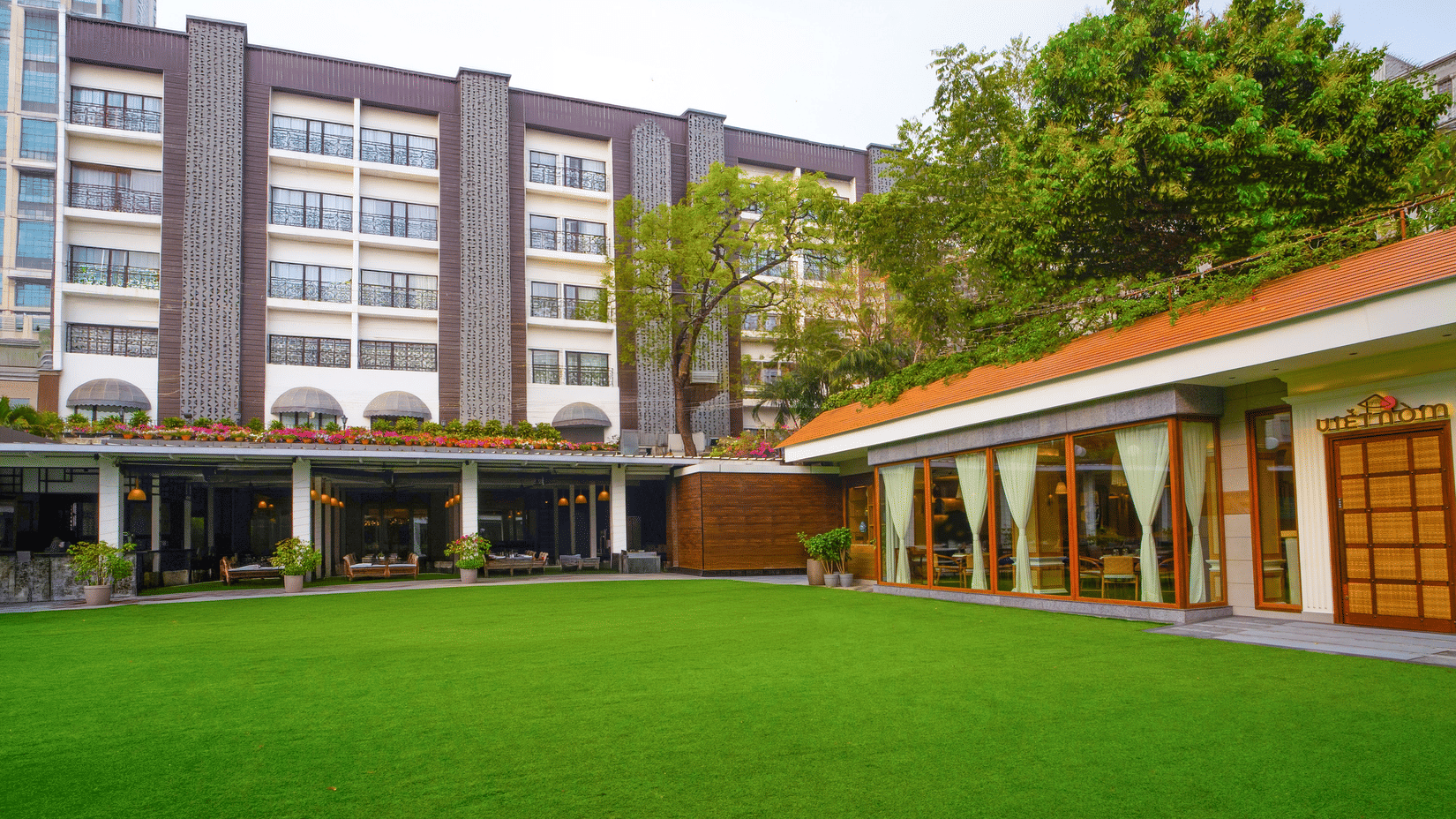 Hotel facade with a manicured lawn and building exterior at Kenilworth Hotel, Kolkata.