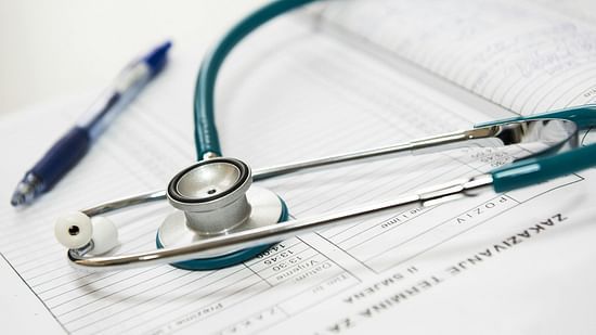 An image of a stethoscope placed on a medical form alongside a pen