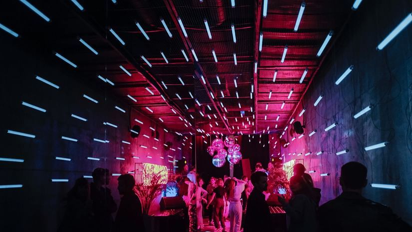 a group of people waiting in queue to enter a club with lights around the circular roof