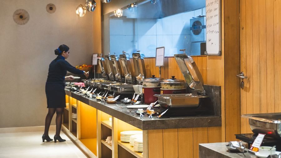 A buffet line with various food warmers and a person standing near it.