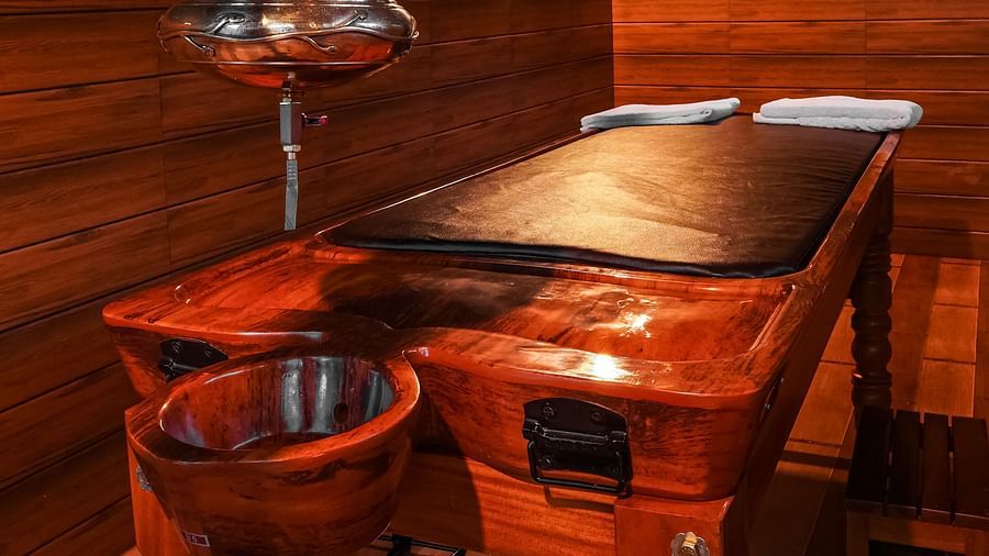 a ayurvedic wellness table with shirodhara machine hanging from top - Holistic Stay Eco Resort, Kannur