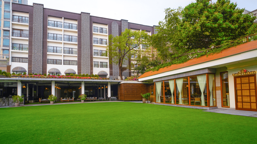Hotel facade with a manicured lawn and building exterior at Kenilworth Hotel, Kolkata.