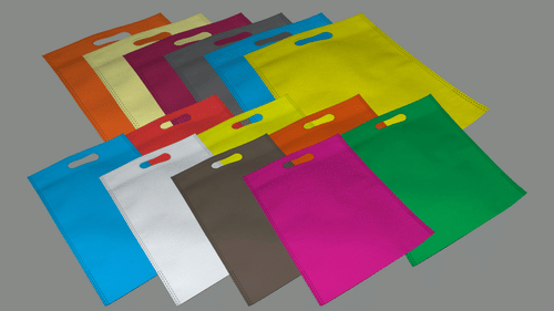 Many cloth bags kept on tops of each other to show the different colours on a table.