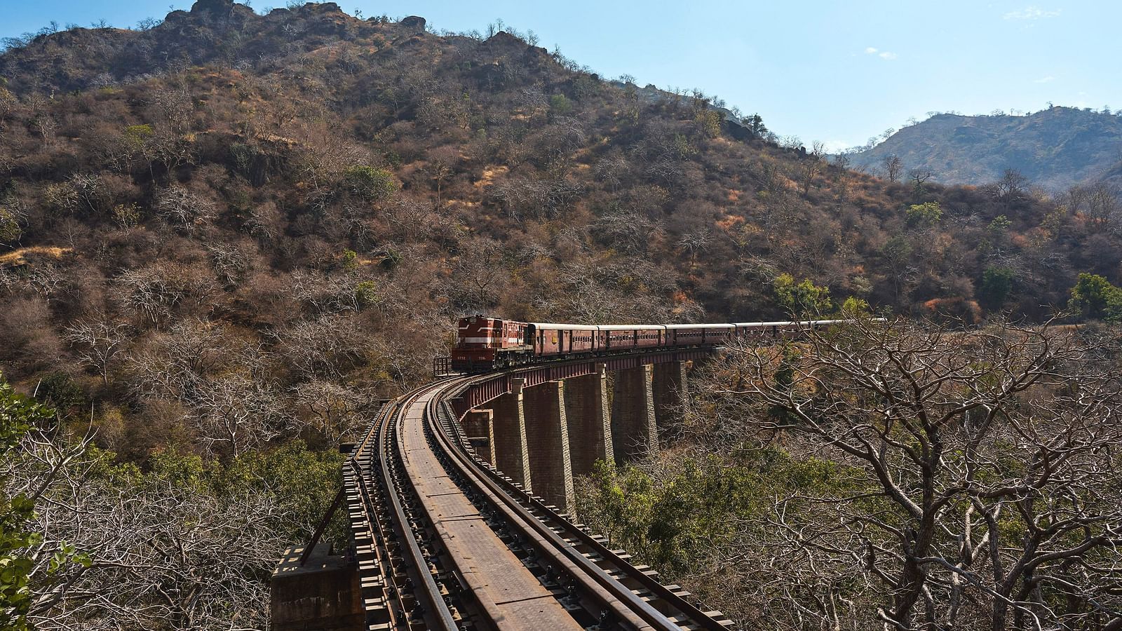 image of a train approaching over a bridge with mountain hills in the background