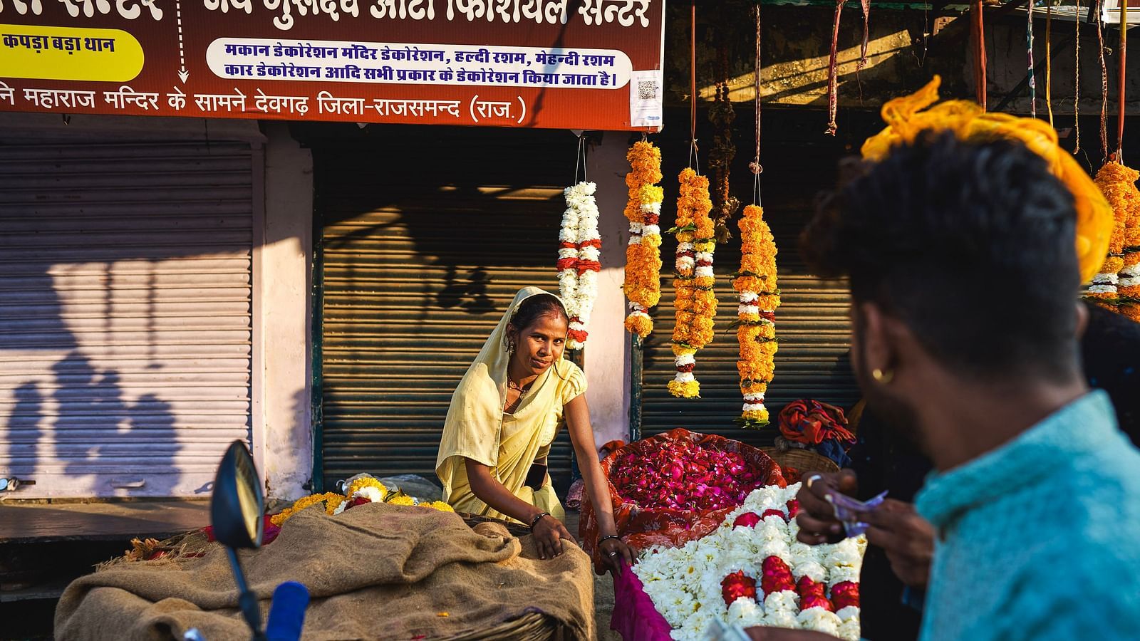 image featuring a woman flower vendor selling various flowers and garlands in a market